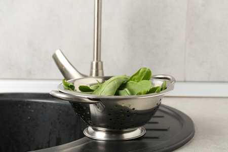 Fresh leaves in colander on sinkの写真素材