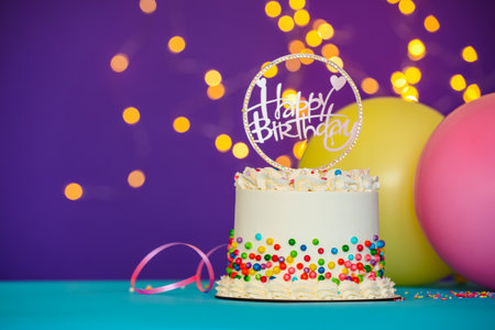 Tasty bento cake with colorful sprinkles, topper and balloons on light blue table against purple background, space for text. Bokeh effectの写真素材
