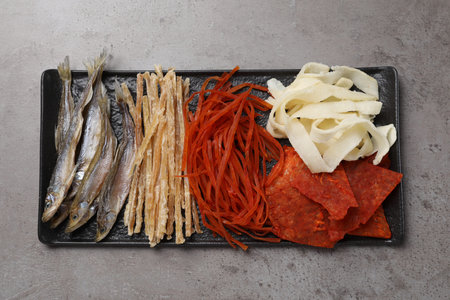 Many different dried fish snacks on gray table, top view