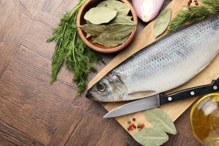 Salted herring, spices and knife on wooden table, flat lay. Space for textの写真素材