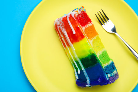 Piece of delicious rainbow cake on light blue table, top viewの写真素材