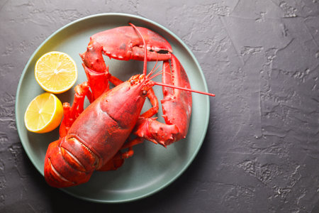 Delicious boiled lobster with lemon pieces on black table, top view. Space for textの写真素材