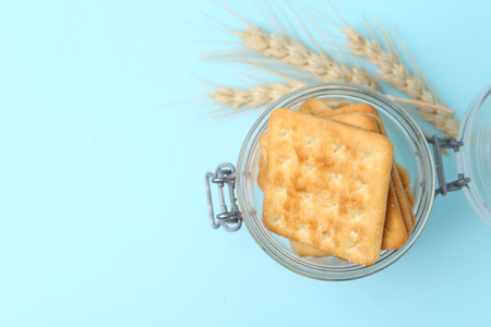 Tasty salty crackers and wheat on light blue background, top view. Space for textの写真素材