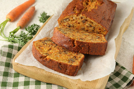 Homemade carrot cake with nuts and vegetables on white textured table, closeup
