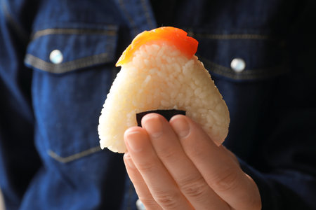 Woman with tasty onigiri (Japanese rice ball) indoors, closeupの写真素材