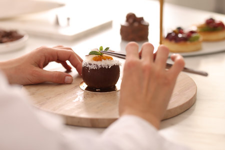 Confectioner making delicious coconut shaped dessert at table, closeupの写真素材