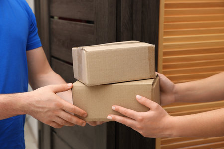 Courier giving parcels to receiver indoors, closeupの写真素材