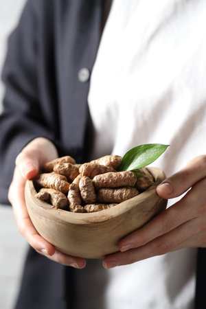 Woman holding bowl with raw turmeric roots, closeupの写真素材