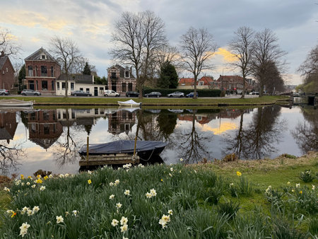 Leiden, Netherlands - March 22, 2025: Beautiful buildings and trees near city canal with moored boats on cloudy dayの写真素材