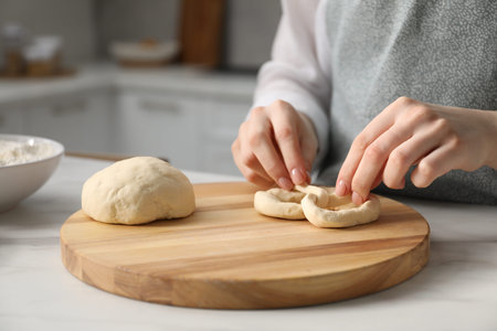 Woman shaping pretzels at table in kitchen, closeup