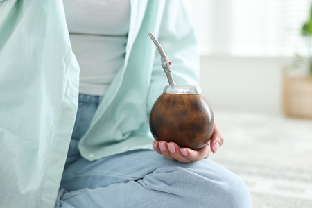 Woman with traditional yerba mate tea at home, closeup. Space for text