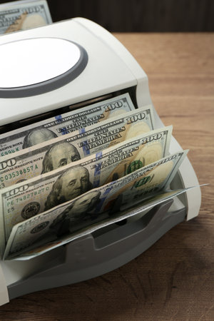 Money counter machine with dollar banknotes on wooden table, closeupの写真素材
