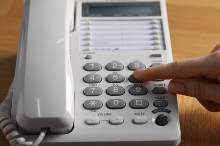 Woman dialing number on telephone at wooden table, closeupの写真素材