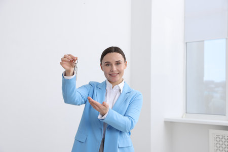 Real estate agent holding key with house shaped keychain indoorsの写真素材