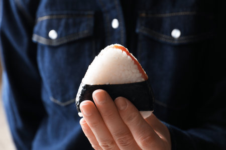 Woman with tasty onigiri (Japanese rice ball) indoors, closeupの写真素材