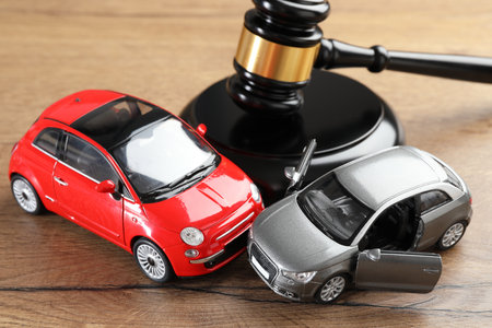Auto accident law. Judge's gavel and toy cars on wooden table, closeupの写真素材