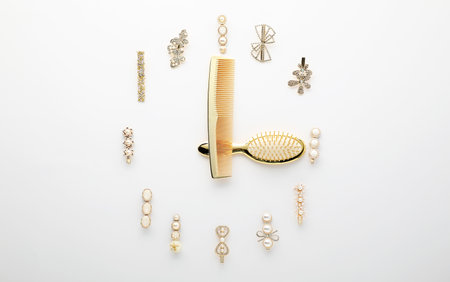 Clock shape made of comb, brush and hair clips on white background, flat layの写真素材
