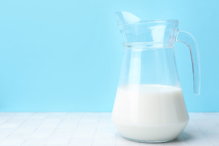 Fresh milk on white table against light blue background. Space for textの写真素材