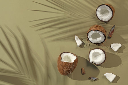 Fresh coconuts and shadow cast by tropical palm on light green background, flat lay. Space for textの写真素材