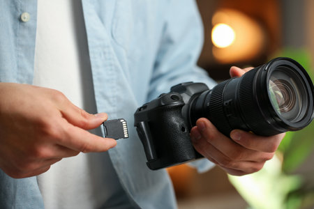 Man inserting SD memory card into photo camera indoors, closeupの写真素材