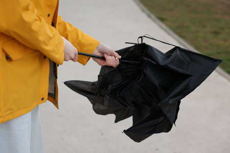Teenage girl with broken umbrella outdoors, closeup
