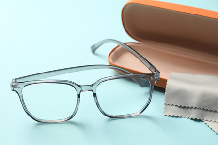 Case, stylish glasses and cleaning cloth on light blue background, closeupの写真素材