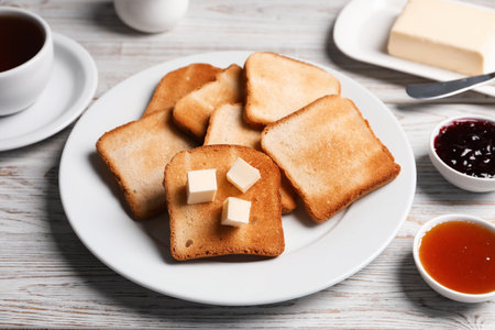 Slices of tasty toasted bread with butter and jam on light wooden table, closeupの写真素材