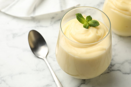 Tasty vanilla pudding with mint served on white marble table, closeupの写真素材