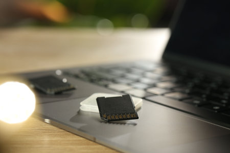 SD memory cards, holder and laptop on wooden table, closeup
