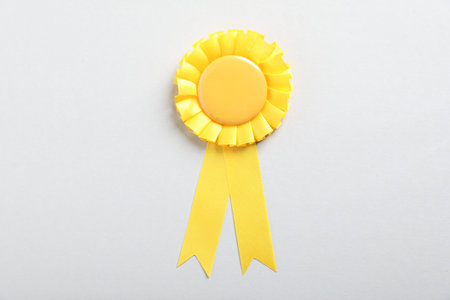 Yellow award ribbon on light gray background, top view