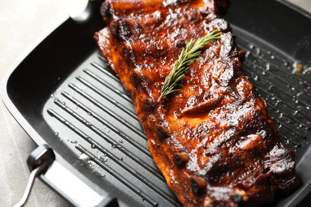 Delicious roasted pork ribs with rosemary on gray table, closeupの写真素材