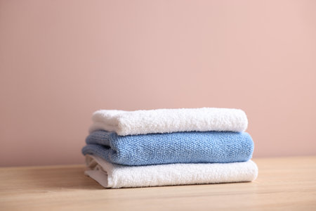 Stack of clean towels on wooden table against beige backgroundの写真素材