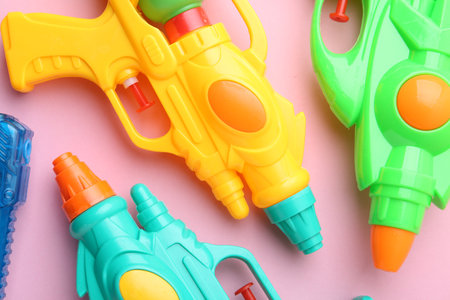 Bright plastic water guns on light pink background, flat layの写真素材