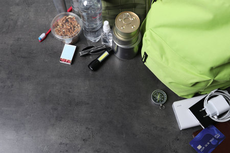 Survival kit. Different emergency supplies on grey table, above view. Space for text