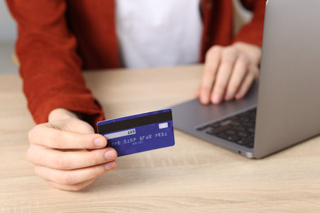 Online payment. Woman with credit card and laptop at wooden table, closeupの写真素材