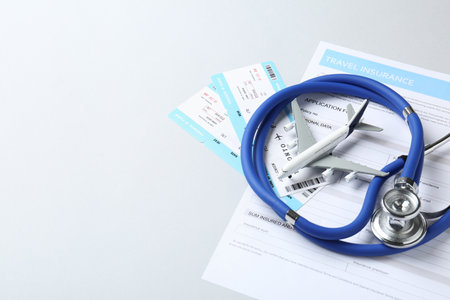 Medical tourism. Travel insurance application form, stethoscope, plane model and flight tickets on light background. Space for textの写真素材