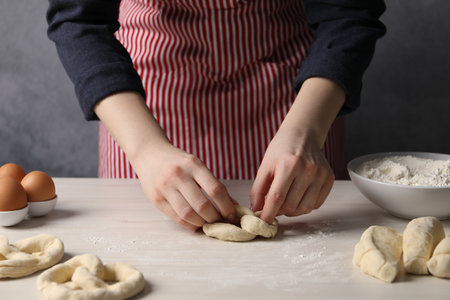 Woman making pretzel at white wooden table, closeupの写真素材