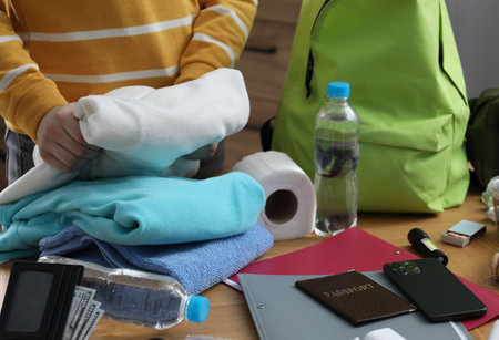 Survival kit. Woman packing different emergency supplies at wooden table indoors, closeupの写真素材
