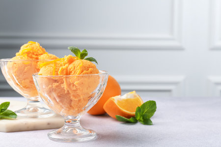 Tasty orange sorbet, fresh fruits and mint on light grey table, closeupの写真素材