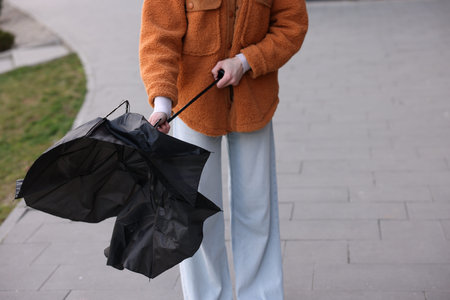 Teenage girl with broken umbrella outdoors, closeupの写真素材
