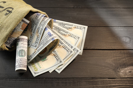 Money bag with dollar banknotes on grey wooden table, closeup. Space for textの写真素材