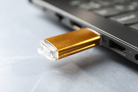 Flash drive connected to laptop on gray textured table, closeupの写真素材