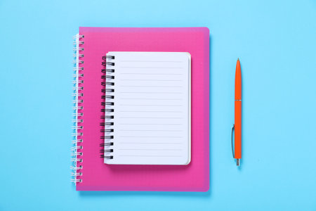 Pen and notebooks on light blue background, flat layの写真素材