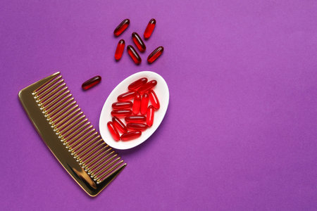 Collagen capsules and comb on purple background, flat lay. Space for textの写真素材