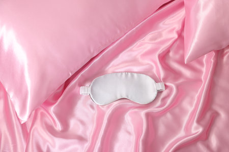 Luxury silk linens and sleep mask on bed, top viewの写真素材