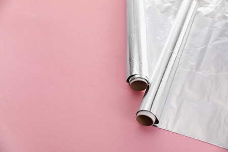 Rolls of aluminum foil on pink background, above view. Space for textの写真素材