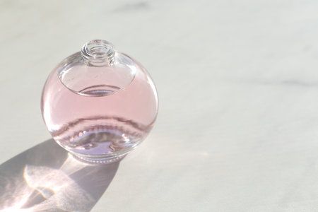 Perfume bottle with aromatic oil on light background, closeup. Space for text