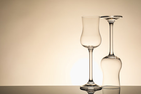 Two empty clean glasses on mirror surface against beige background. Space for textの写真素材