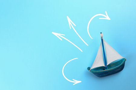 Guide. Arrows pointing in different directions in front of toy ship on light blue background, top...