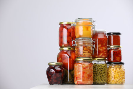 Many jars with different pickled products on light grey table, space for textの写真素材